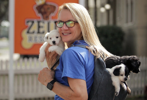 Michelle Ingram owner of Zeus Place and Zeus' Rescues in New Orleans Louisiana holds a rescue puppy and carries two puppies in the Pang Wangle Touring Convertible Backpack